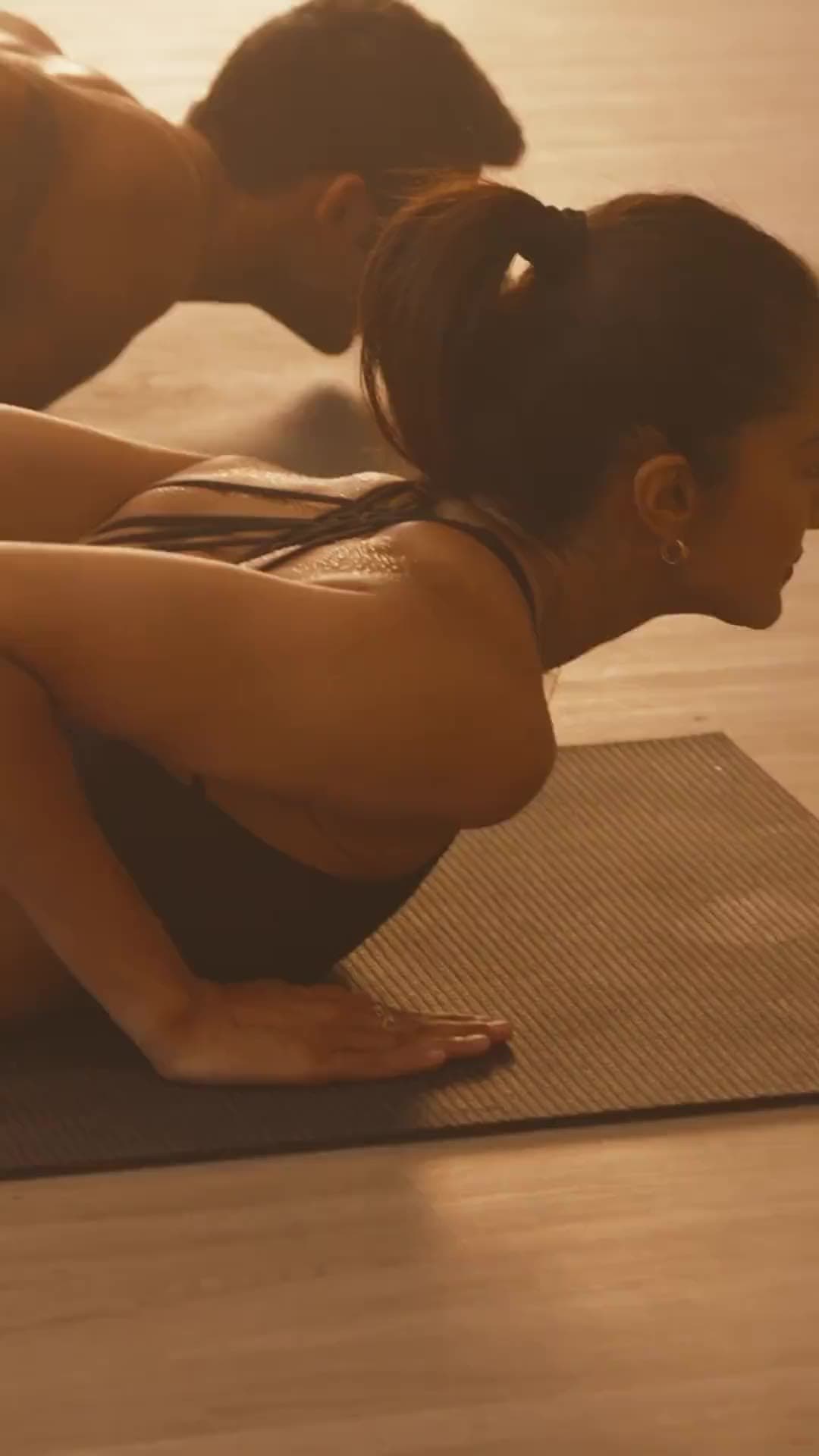 A practitioner mid-flow on the mat in the warm-lit hot yoga room at Ignite + Aliign, Bangalore
